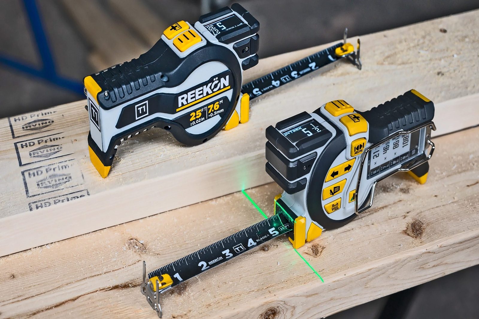 Two tape measures lie on a wooden surface, one extended with a green laser line, indicating measurement on the wood, in a workshop setting.