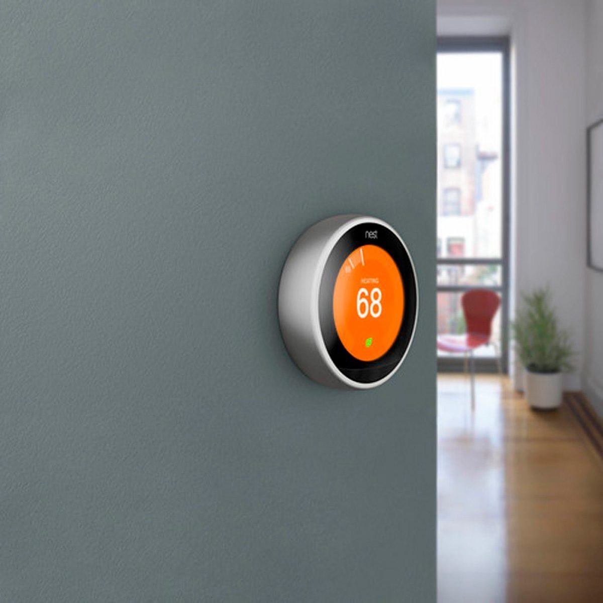 A round smart thermostat displays a temperature of 68°F, mounted on a gray wall, with a modern interior visible in the background.