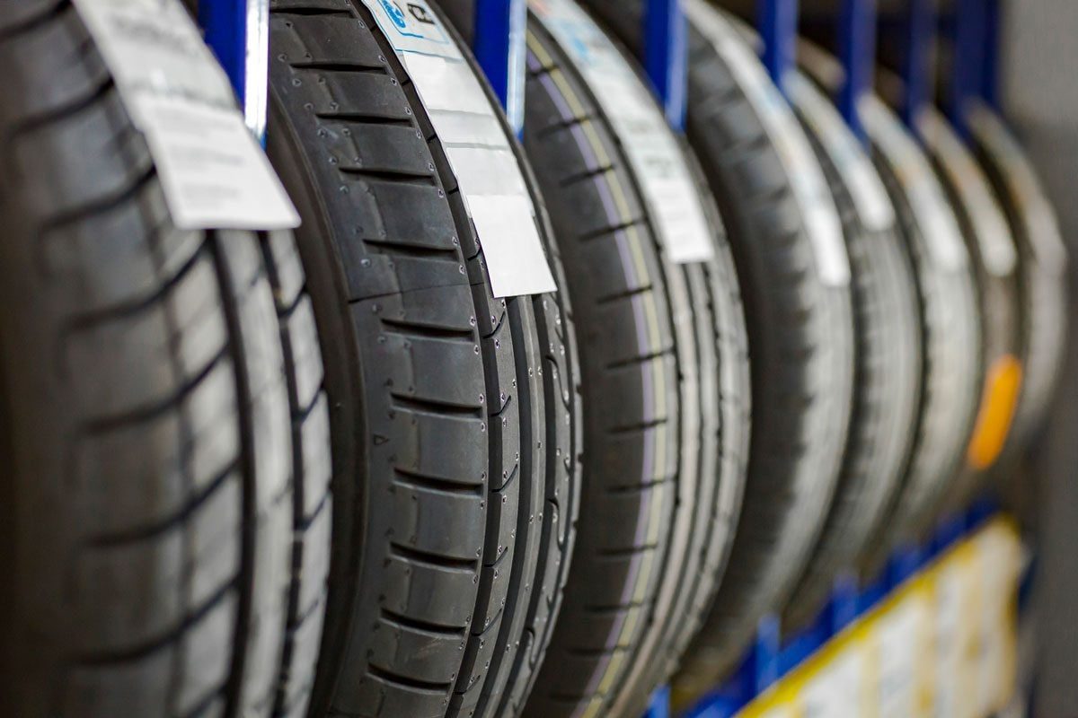 Tires are displayed vertically on blue racks, showcasing their tread patterns and labels in a well-lit storage area.