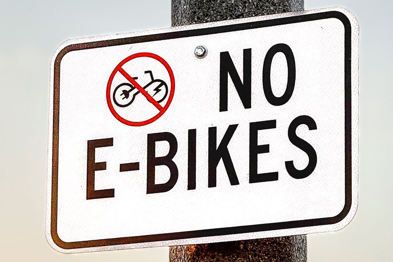 Use Not Permitted sign. Restricted No Electric Bikes zone sign with blue sky background.