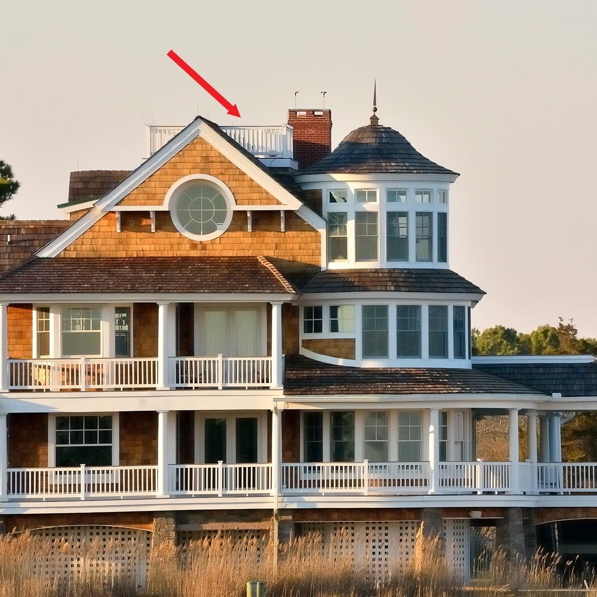 Three-story coastal house with a porch on the roof, and a red arrow pointing to the roof porch