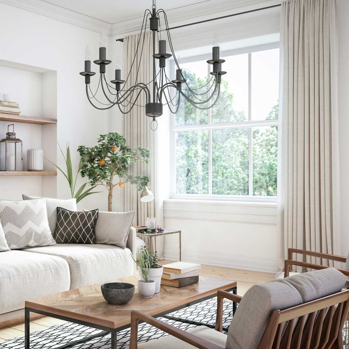 A modern living room features a chandelier hanging above a wooden coffee table, with a sofa and plants, illuminated by natural light from th