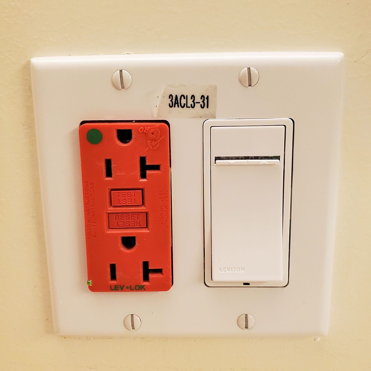 Close-up of a wall plate, with a switch and red-colored emergency backup power outlets in a medical setting in San Francisco, California