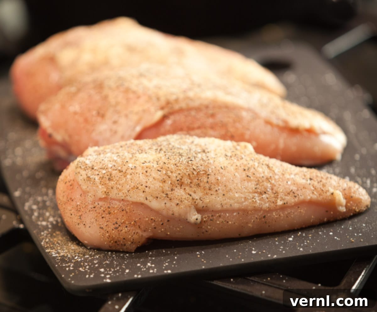 Roast Chicken -4939 Αλατοπιπερωμένο ωμό στήθος κοτόπουλου σε μαύρο ξύλο κοπής.