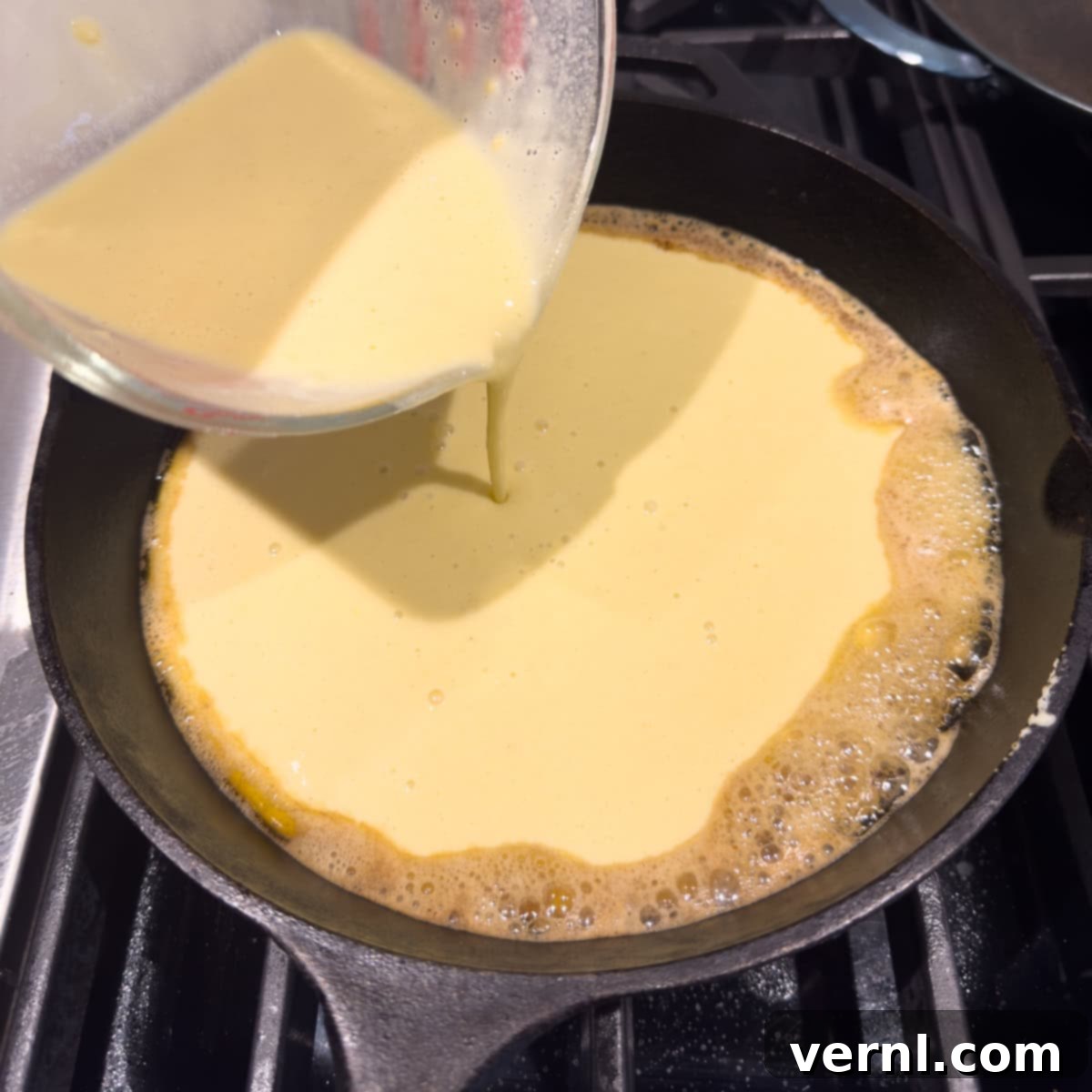 Ρίχνουμε ζύμη για μια german oven pancake σε ένα καυτό μαντεμένιο τηγάνι