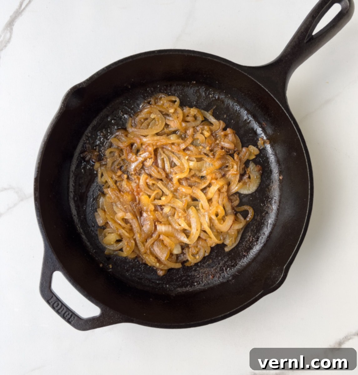 Χοιρινές Μπριζόλες Ξινής Κρέμας 7 Caramelized onions in black pan.