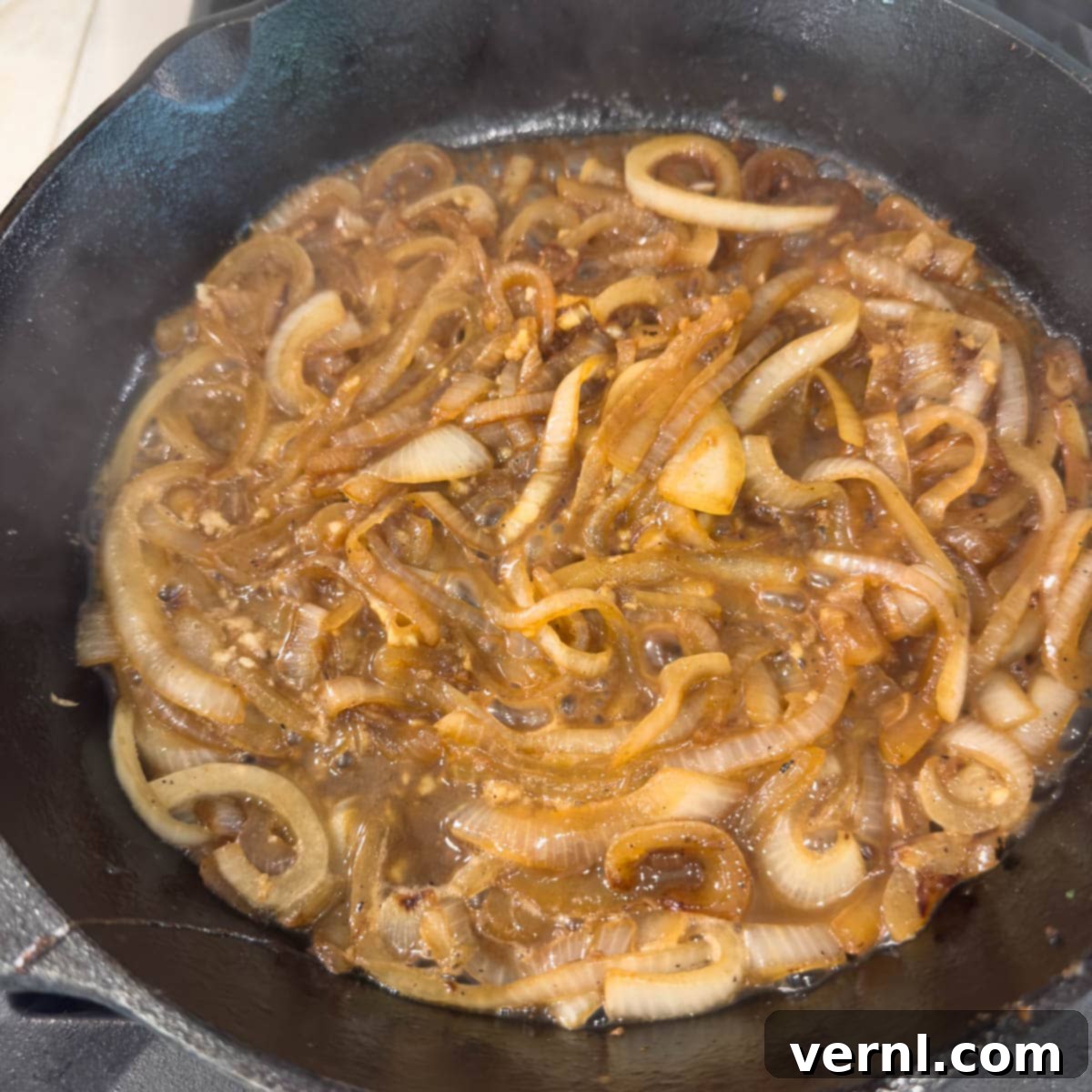 Χοιρινές Μπριζόλες Ξινής Κρέμας 8 Golden brown caramelized onions in a black skillet deglazing with wine.