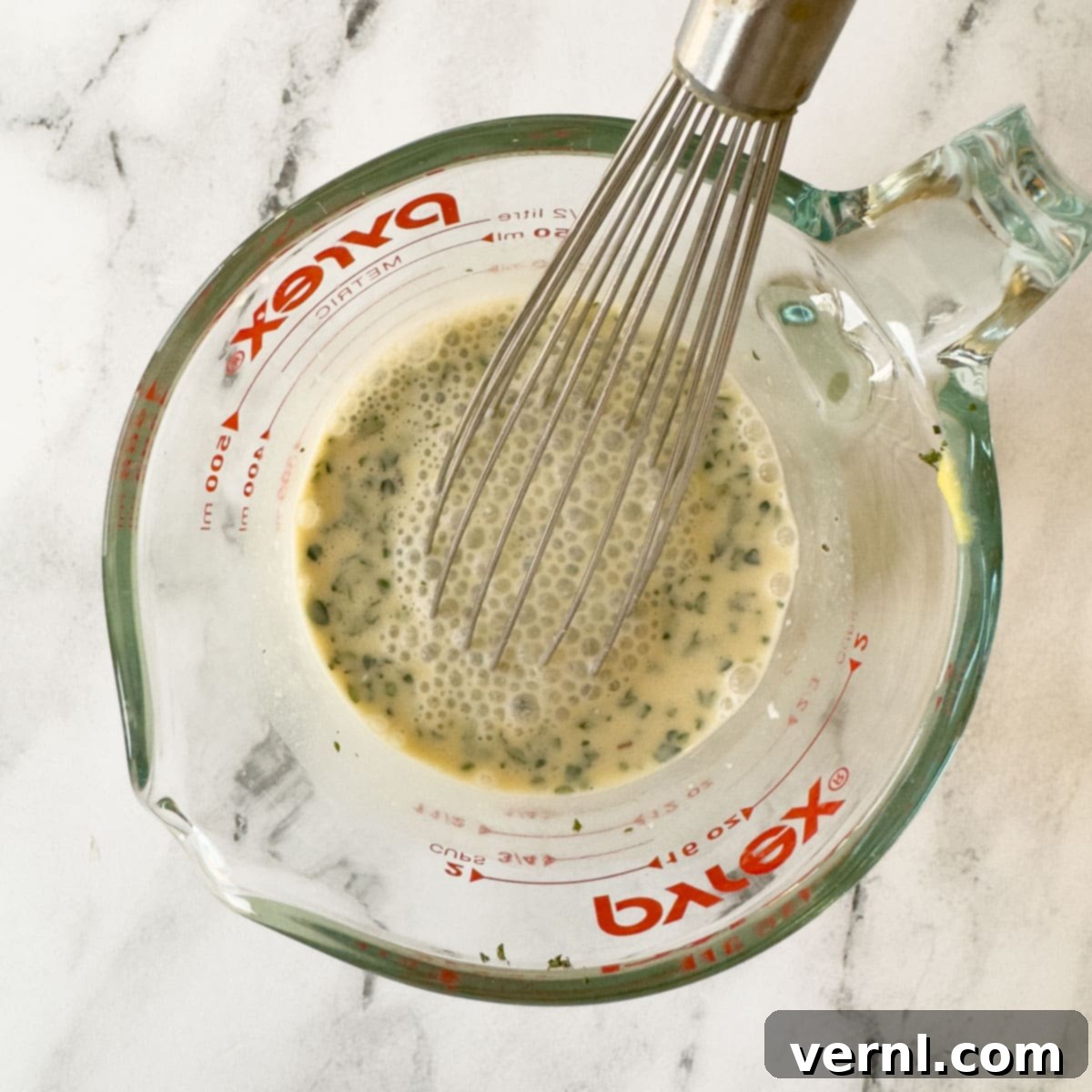 Χοιρινές Μπριζόλες Ξινής Κρέμας 9 Sauce ingredients being whisked together in a pyrex glass measuring cup.