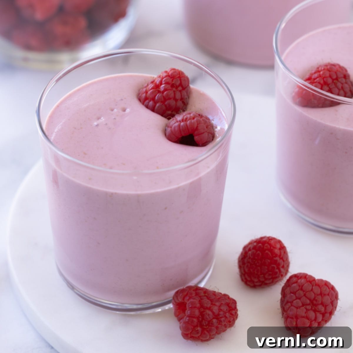 Σμούθι με Σμέουρα 5 Ένα φωτεινό ροζ smoothie με μούρα και φρέσκα σμέουρα μέσα στο ποτήρι.