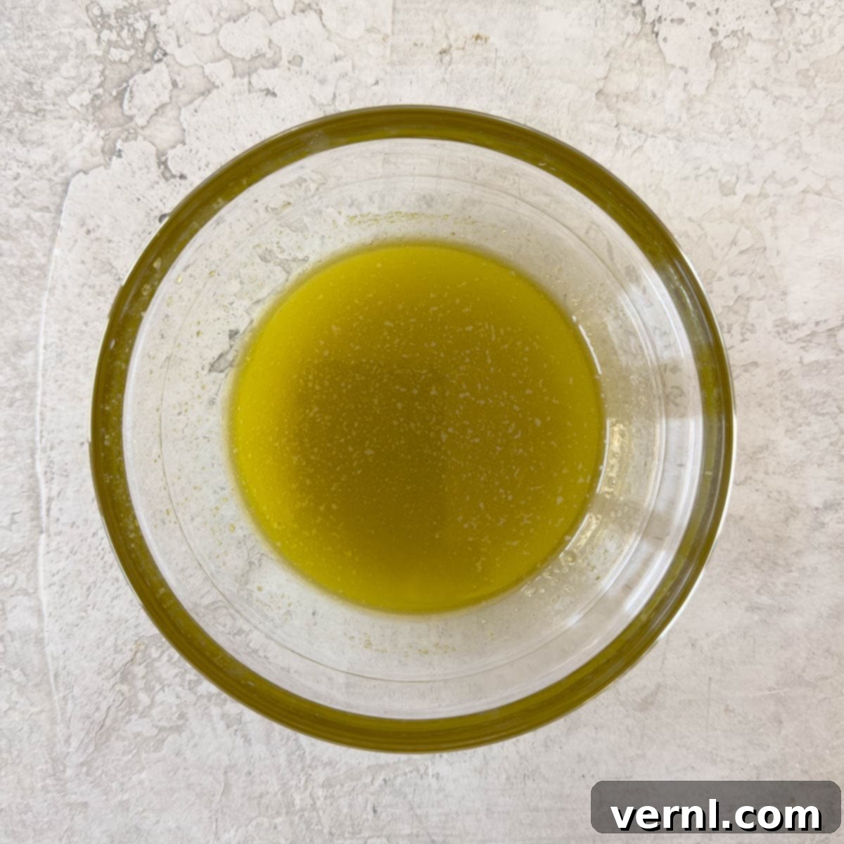 Πώς να φτιάξετε κρουτόν χωρίς γλουτένη 4 Λιωμένο βούτυρο, εξαιρετικό παρθένο ελαιόλαδο και σκόρδο σε ένα μικρό γυάλινο μπολ, έτοιμο για να ανακατευτεί με το ψωμί.