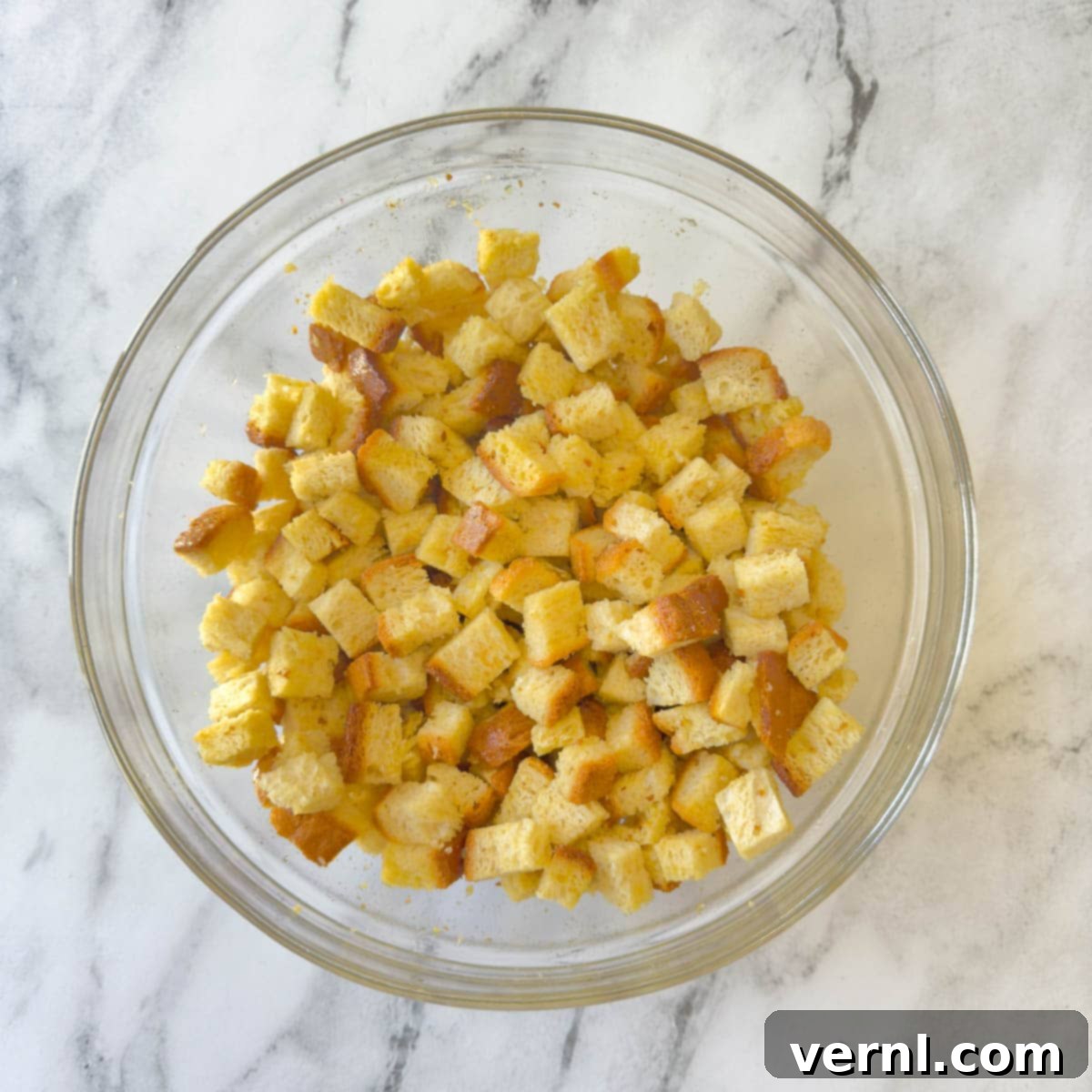 Σαλάτα Ζυμαρικών Καίσαρα με Κοτόπουλο 5 Bread cubes tossed with butter and olive oil in a glass bowl.