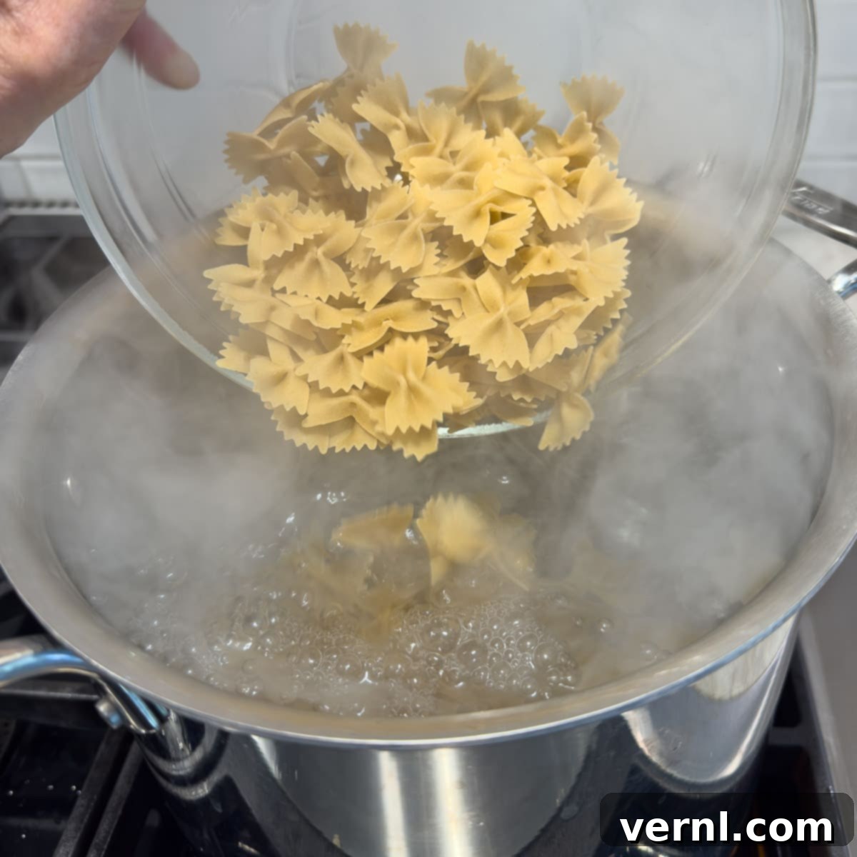 Σαλάτα Ζυμαρικών Καίσαρα με Κοτόπουλο 6 Pouring dry pasta into a large pot of boiling water to cook.