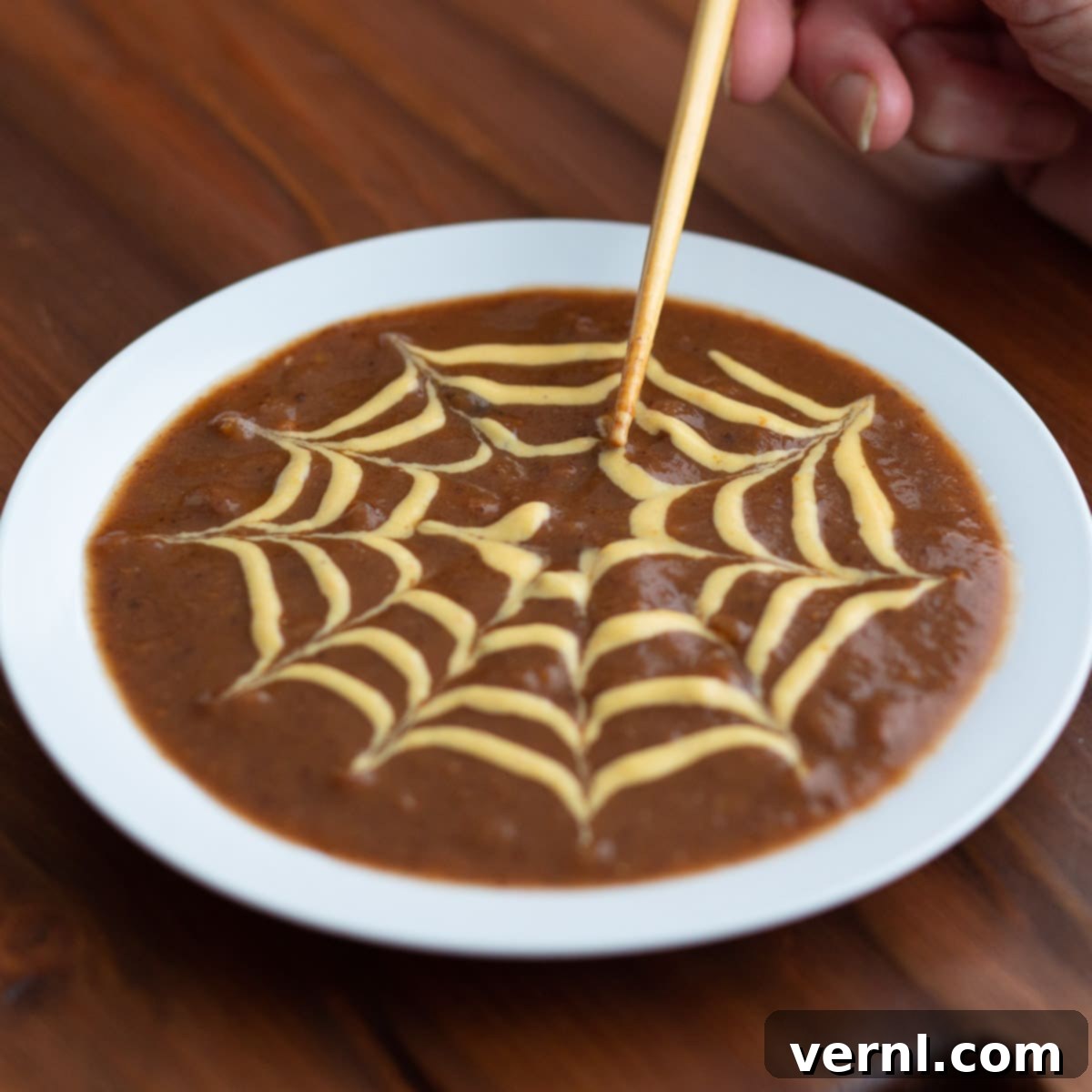 Soup Spider Web-2 Δημιουργώντας ένα σχέδιο ιστού αράχνης πάνω από σούπα μαύρων φασολιών ως γαρνιτούρα.
