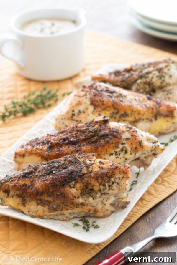 Κοτόπουλο με Βελούδινη Σάλτσα 2 Braised chicken breasts on a platter with gravy boat of cashew sauce.