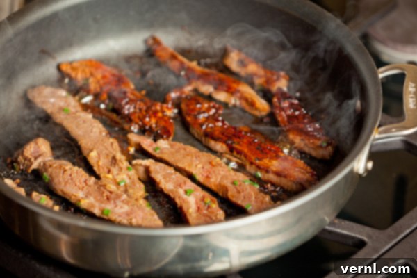 Ginger Flank Steak-6638 Stir-fry με flank steak σε καυτό τηγάνι με καπνό να αναδύεται.
