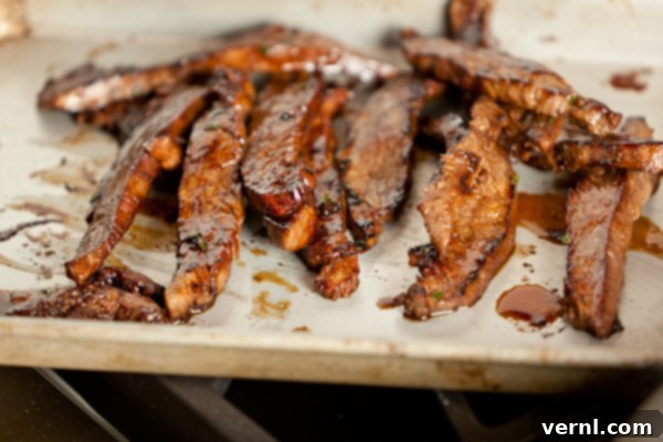 Ginger Flank Steak-6650 Τελικές μαγειρεμένες λωρίδες flank steak σε δίσκο στρωμένο με λαδόκολλα.