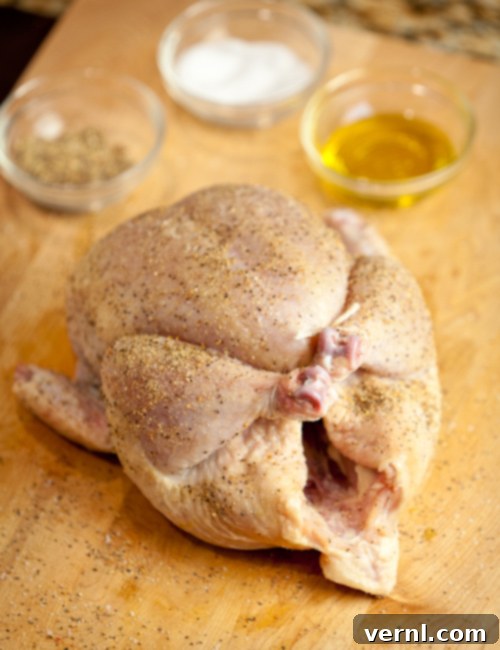 Whole Roast Chicken -0378 A seasoned whole chicken, legs tied and ready for roasting on a wood cutting board.