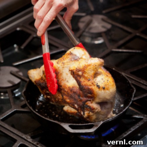 Whole Roast Chicken -0400 A whole chicken being seared in a cast iron pan on all sides before roasting