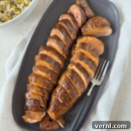 Καπνιστό χοιρινό ψαρονέφρι 9 BBQ glazed smoked pork tenderloin sliced on a gray platter for serving.