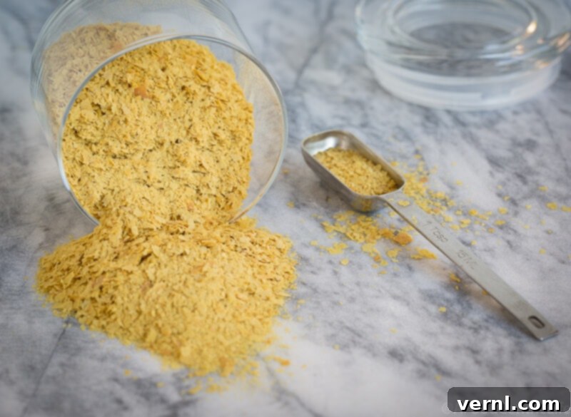 nutritional yeast | AFoodCentricLife.com Χρυσαφένια θρεπτική μαγιά χυμένη σε έναν πάγκο με ένα κουταλάκι του γλυκού.