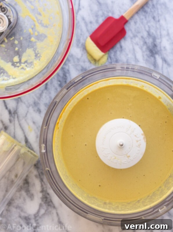 vegan cheese sauce | AFoodCentricLife.com Χρυσαφένια βίγκαν τυροσαλάτα σε ένα μπολ επεξεργαστή τροφίμων.