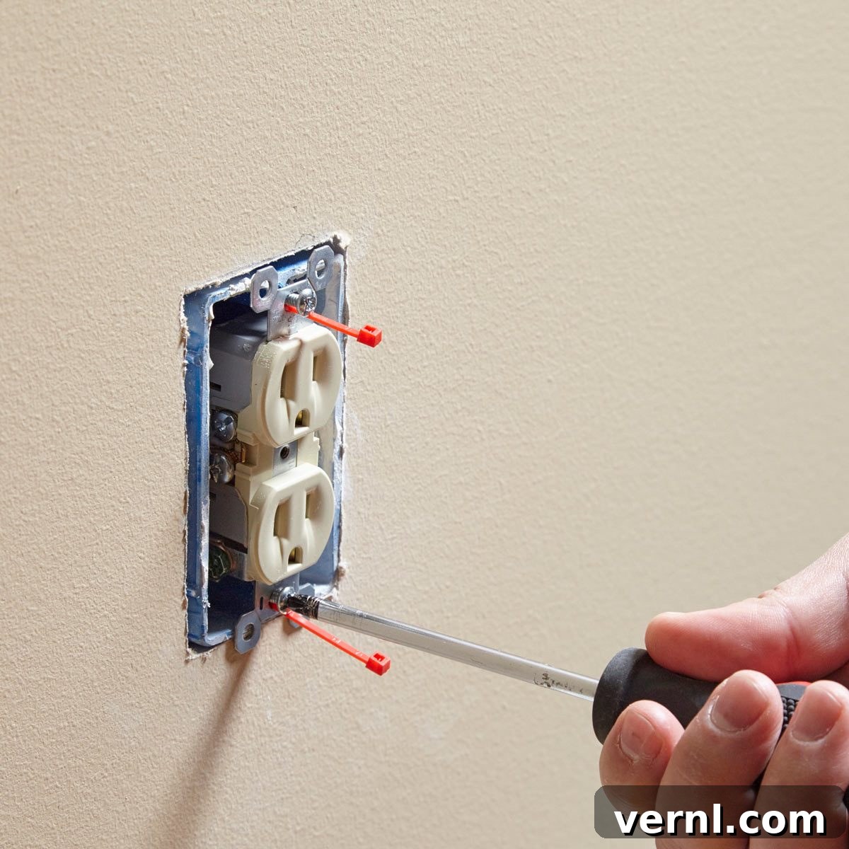 Person attempting to fix a loose electrical outlet or switch within a wall, symbolizing the common challenge of a 'screwy electrical box'.
