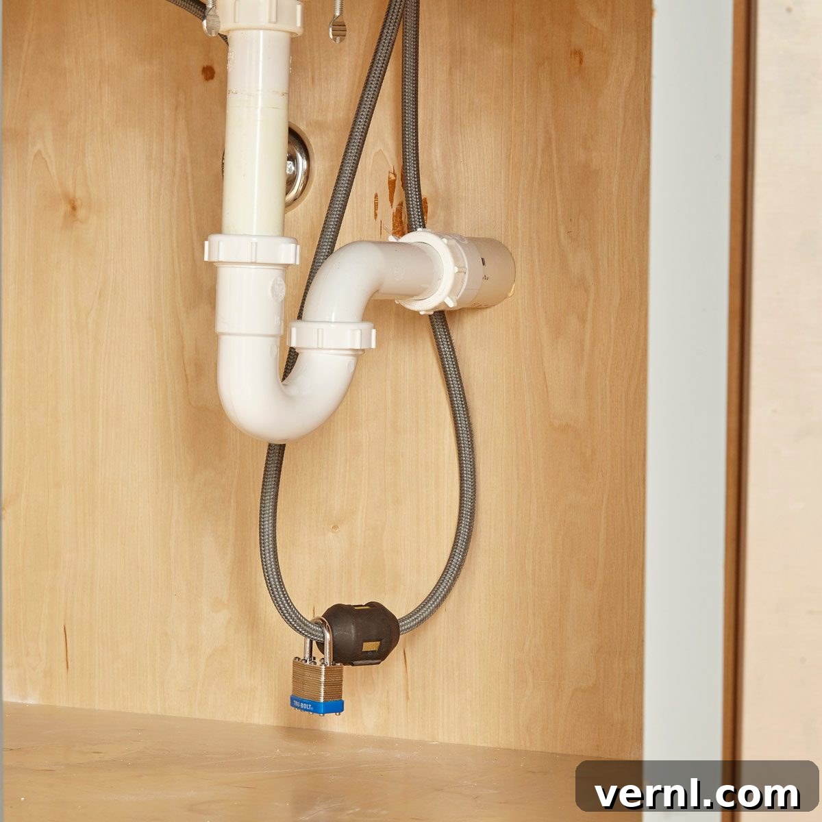 Man adding weight to a pullout kitchen faucet hose under the sink with a padlock