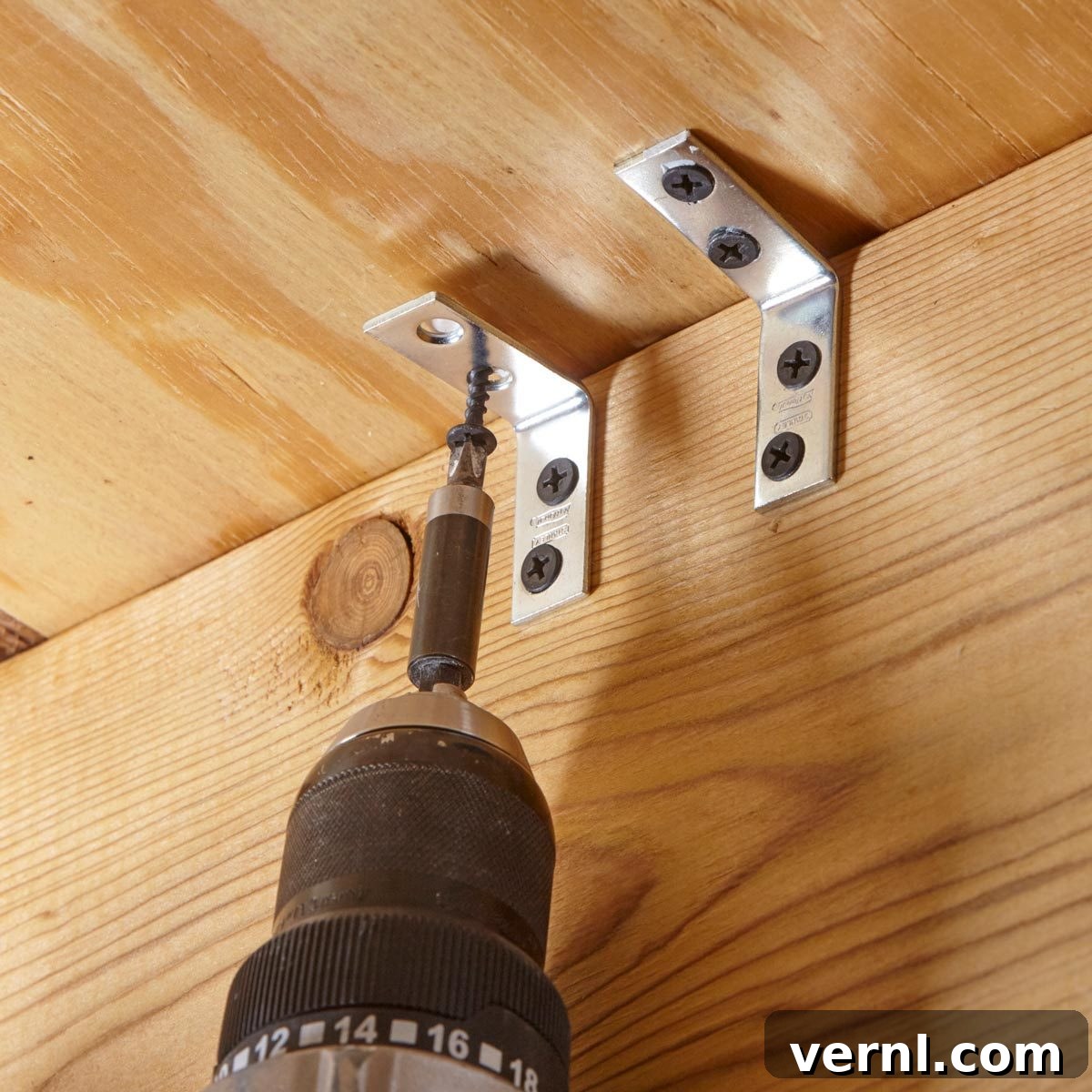 A simple corner bracket fixed to a floor joist with a screw driven into the subfloor, demonstrating a squeaky floor repair hack.