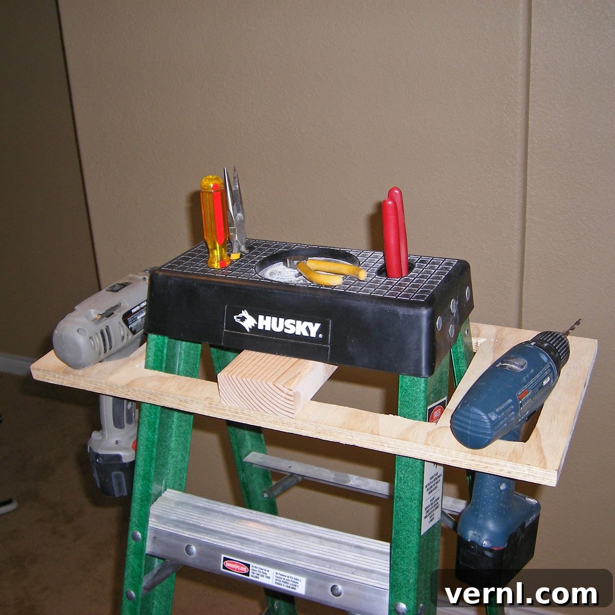 A simple wooden Ladder Caddy providing a stable platform for tools on a stepladder, enhancing organization and safety during work