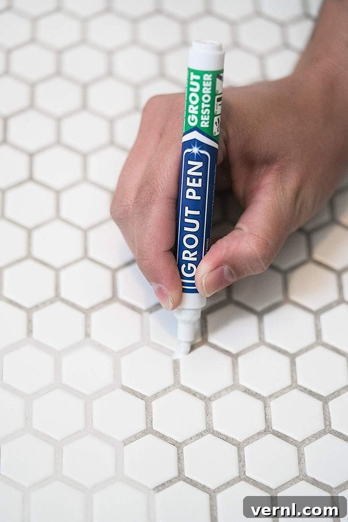 Grout Pen: Effortless Shine, Permanent Results 2 Hand holding a white grout pen, demonstrating its use on tile grout.