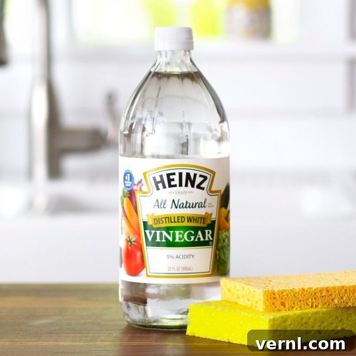 Vinegar and cleaning sponges on wooden surface