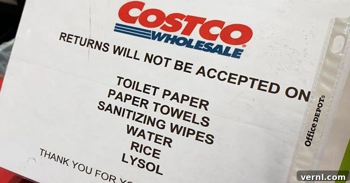Costco store sign indicating no returns on essential items like toilet paper, paper towels, wipes, water, rice, and Lysol during a period of high demand.