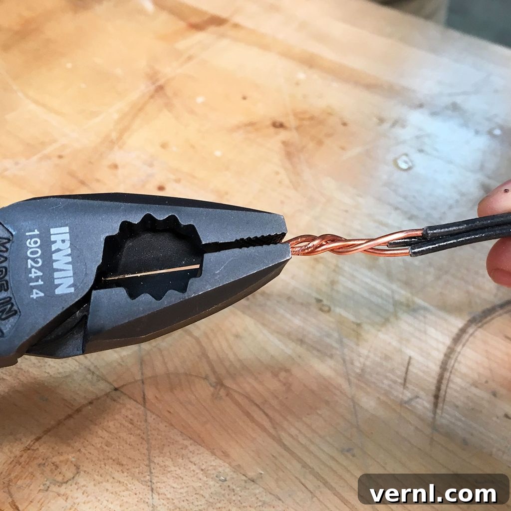 A pair of lineman's pliers securely grips twisted copper wires, demonstrating proper technique for wire manipulation on a wooden surface.