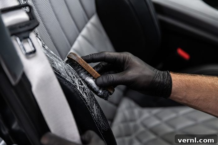 DIY vs. Pro Car Detailing: The Ultimate Cost Comparison 3 Car detailing studio worker cleaning car interior and car leather seats with a brush.