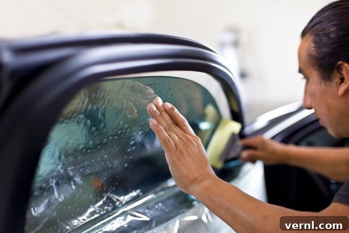 Tint Your Car Windows Like a Pro 2 Man installing window tinting on car.