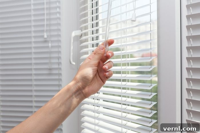 Safeguard Your Home: The Complete Security Guide 2 Close-up of hands drawing blinds on a window, enhancing home privacy and security.