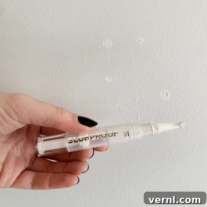 Flawless Walls, No Mess: My Slobproof Paint Pen Discovery 2 hand holding a paint pen with white paint on a wall