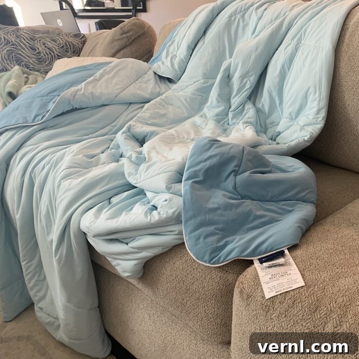 Evercool Comforter Review: Experience Cooler, More Restful Sleep 2 Cooling Comforter On Couch: A detailed shot of the Rest Evercool Cooling Comforter draped elegantly over a modern couch, highlighting its Aqua Blue color and sleek texture. The image conveys comfort and contemporary design, suggesting its seamless integration into any living space.
