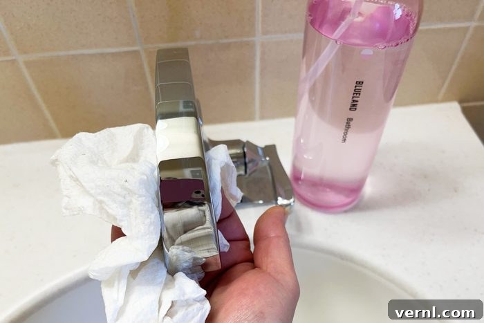 Blueland Cleaning Kit: My Sparkling Home, My Plastic-Free Choice 3 Hand cleaning a bathroom sink faucet with a pink bottle from the Blueland Cleaning Kit, showcasing practicality