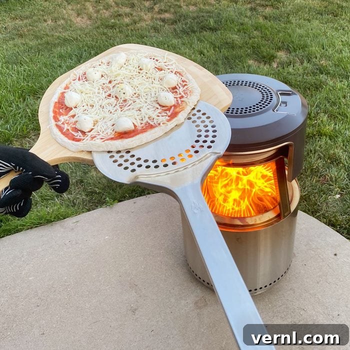 Solo Stove Pi Fire Review: The Ultimate Fire Pit Pizza Upgrade 3 putting a pizza in the Solo Stove Pi Fire