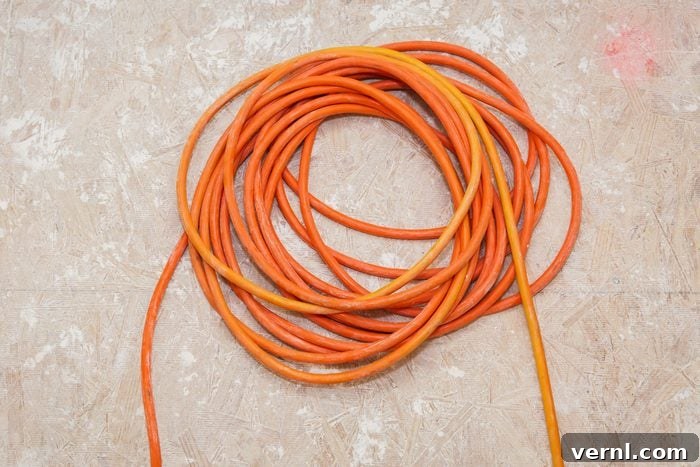 Mastering Extension Cords Your Guide to Safe and Effective Use 2 Orange heavy-duty extension cord coiled on a wooden floor, ready for use with power tools for a construction project.