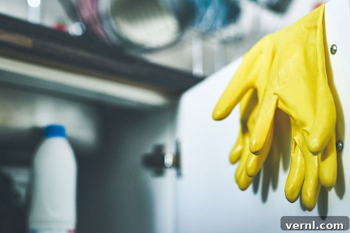 a pair of rubber gloves hanging over a door underneath a kitchen sink at home