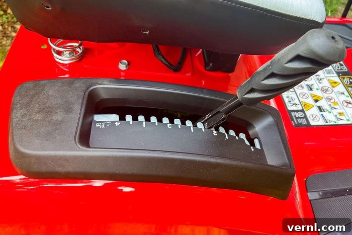 Craftsman's Electric Rider: Taming Tight Spaces with Ease 2 A black gear shift lever is positioned over a numbered console, indicating speed adjustments on a bright red lawn mower in a grassy context.