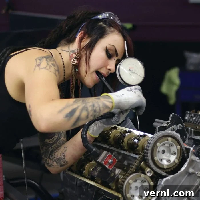 A young woman diligently inspecting the engine of a car, tools neatly laid out nearby, embodying focus and expertise.