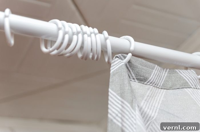 Time to Ditch Your Shower Curtain? 3 Close-up of an incomplete hanging a gray curtain in the bathroom shower