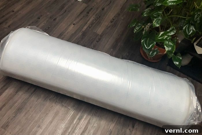 Zinus Green Tea Memory Foam Mattress: Three Years Later, Our Full Review 4 A roll of plastic wrap sitting on a wooden floor, representing a mattress being unboxed.