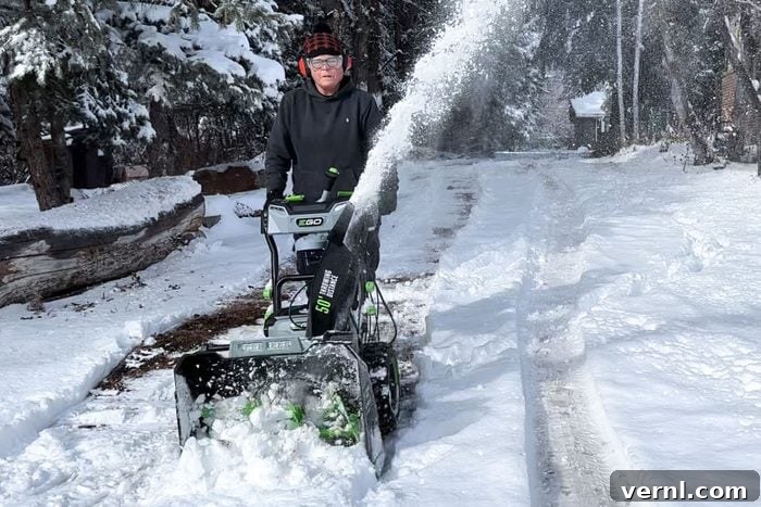 I Put the EGO Cordless Two-Stage Snow Blower to the Test and It Blew Me Away 3 A woman efficiently clearing snow with the Ego Cordless Two-Stage Snow Blower, highlighting its ease of use and powerful performance.