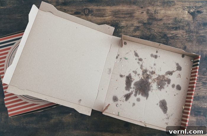 Don't Trash That Box The Truth About Pizza Box Recycling 2 Empty, grease-stained cardboard pizza box on a dark surface