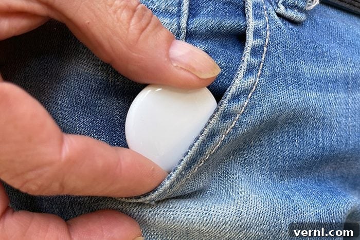 10 Brilliant AirTag Ideas for Your Everyday 3 A hand keeping an Apple AirTag in a jeans pocket, subtly for tracking