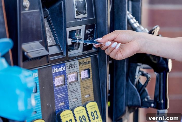 Gas Rewards Programs That Deliver Real Savings at the Pump 3 A woman's hand holding a credit card, tapping it against a gas pump's card reader to pay for fuel, emphasizing convenience and modern payment methods.
